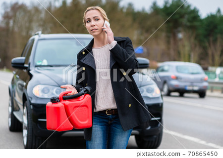 Woman has car with empty gas tank calling for help on phone 70865450