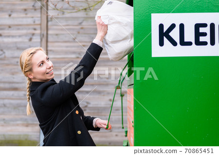 Woman putting old or used clothes into donation bin Woman putting old or used clothes into donation bin 70865451
