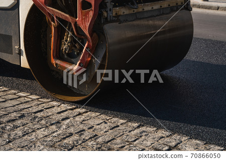 Asphalt road roller with heavy vibration roller compactor press new hot asphalt on the roadway on a road construction site. Heavy Vibration roller at asphalt pavement working. Repairing. 70866050