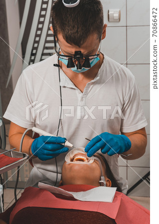 The dentist removes tartar using ultrasound, the patient at the dentist. The dentist removes tartar using ultrasound, the patient at the dentist. 70866472