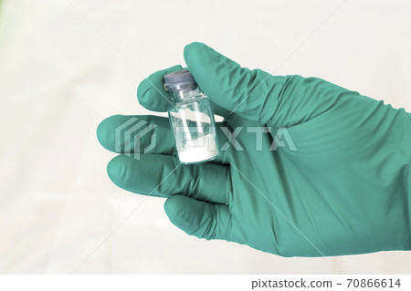 Vial with white powder of medicine, vaccine or poison in hand in sterile glove 70866614
