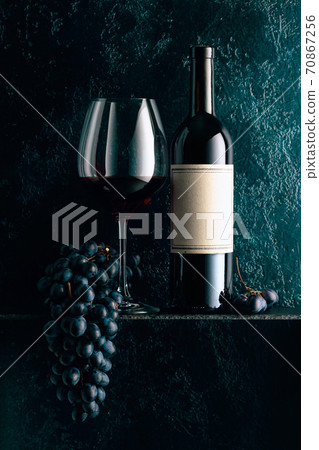 Red wine and blue grapes on an old dark blue background. Red wine and blue grapes on an old dark blue background. 70867256