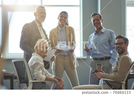 Strong and successful team. Group of happy multiracial business people smiling at camera while having a meeting at office Strong and successful team. Group of happy multiracial business people smiling at camera while having a meeting at office 70868133