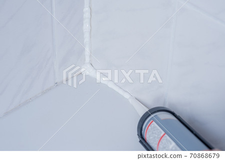 Plumber Applying silicone sealant to the tile joint 70868679
