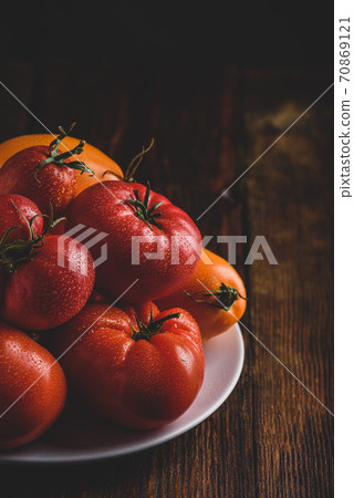 Fresh red and yellow tomatoes on plate 70869121