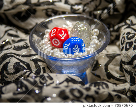 Three fortune-telling dice placed in a tight glass of pearl beads 70870670