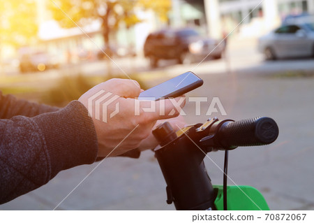Close up image of a man on an electric scooter paying online by mobile phone Close up image of a man on an electric scooter paying online by mobile phone 70872067