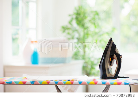 Ironing board and iron with folded clothes. Ironing board and iron with folded clothes. 70872998
