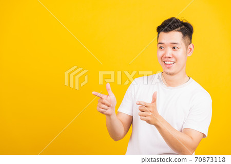 young man smiling standing pointing finger to the side away young man smiling standing pointing finger to the side away 70873118