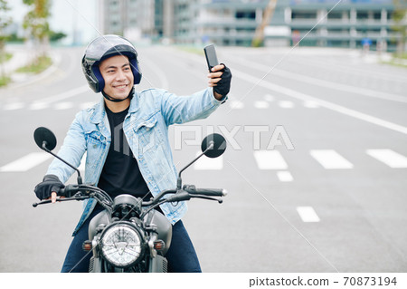 Motorcyclist taking selfie 70873194
