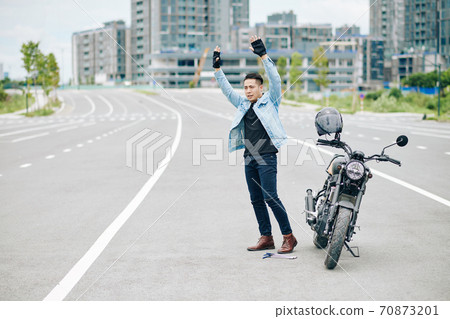 Motorcyclist standing on road Motorcyclist standing on road 70873201