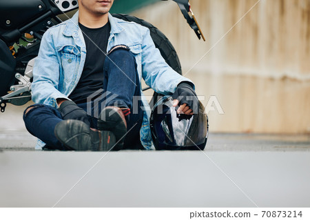 Motorcyclist resting on ground Motorcyclist resting on ground 70873214