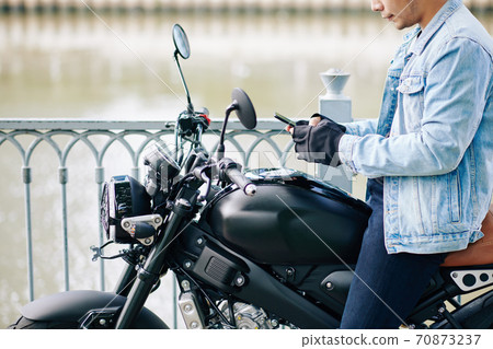 Motorcyclist checking phone Motorcyclist checking phone 70873237