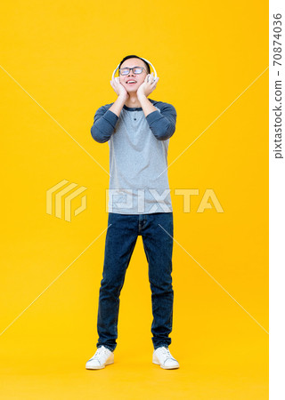 Happy Asian man wearing headphones listening to relaxing music with eyes closed 70874036