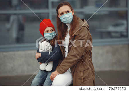 A European mother in a respirator with her daughter are standing near a building.The parent is teaching her child how to wear protective mask to save herself from virus A European mother in a respirator with her daughter are standing near a building.The parent is teaching her child how to wear protective mask to save herself from virus 70874650