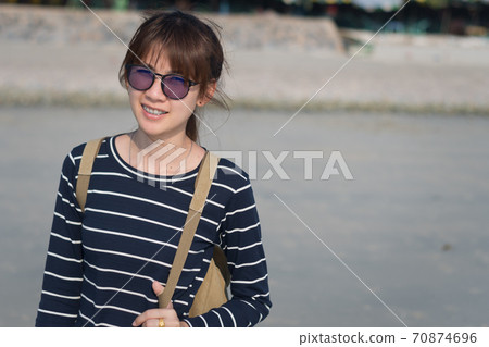 Close-up an Asian woman wearing sunglasses looking out over the sea at sunset. Close-up an Asian woman wearing sunglasses looking out over the sea at sunset. 70874696