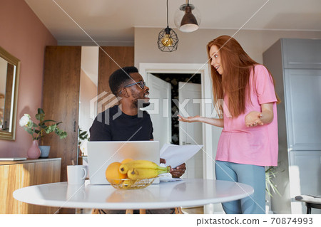 emotional discussion of interracial couple holding documents at home 70874993