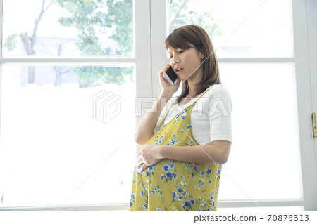 Pregnant woman making a phone call 70875313
