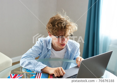 schoolboy is typing report on laptop, do homework schoolboy is typing report on laptop, do homework 70876188
