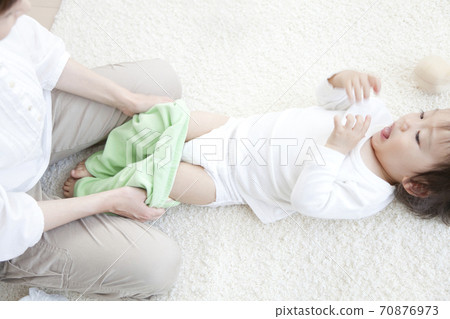 Mother exchanging diapers for children 70876973