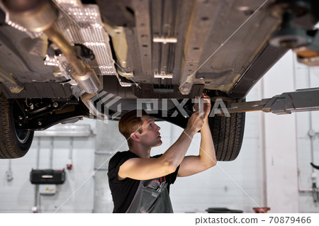 male mechanic is working on a vehicle in a car service, alone male mechanic is working on a vehicle in a car service, alone 70879466