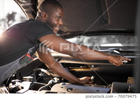 repairing in action. hardworking guy employee in uniform works in the automobile salon repairing in action. hardworking guy employee in uniform works in the automobile salon 70879475