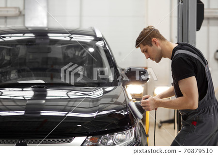 car detailing and polishing concept. young professional car service male worker with orbital polisher car detailing and polishing concept. young professional car service male worker with orbital polisher 70879510