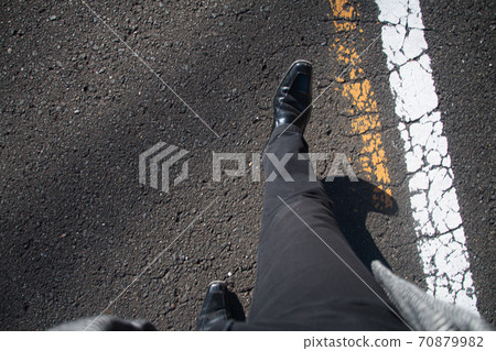 一個人的腳在道路上行走的主觀視角。冬天,黑色的褲子和外套 一個人的腳在道路上行走的主觀視角。冬天,黑色的褲子和外套 70879982
