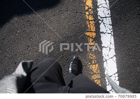 Foot subjective viewpoint of a man walking on the road. Winter, black trousers and coat 70879985