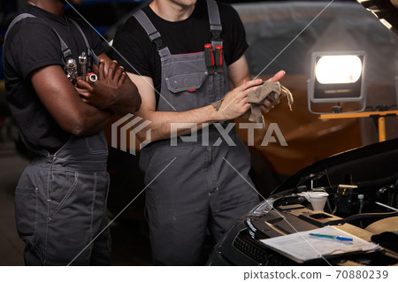 two auto mechanics discuss problems of repairing a car two auto mechanics discuss problems of repairing a car 70880239