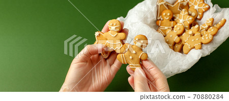 Woman hands in protective gloves holding gingerbread man in facemask on natural shades of green background, pandemic new normal, 2021 New Year card, Christmas traditional sweetness, copy space Woman hands in protective gloves holding gingerbread man in facemask on natural shades of green background, pandemic new normal, 2021 New Year card, Christmas traditional sweetness, copy space 70880284