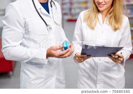 two caucasian pharmacists are discussing medication, using a digital tablet 70880380