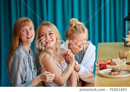 girlfriends laugh, have fun while sitting in restaurant girlfriends laugh, have fun while sitting in restaurant 70881863