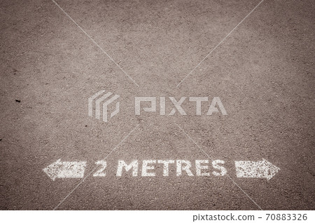 Social distancing road painted sign recommending staying 2 metres apart Social distancing road painted sign recommending staying 2 metres apart 70883326