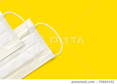 Medical face masks on yellow background. Protection against coronavirus, flu and other airborne infection. Copy space Medical face masks on yellow background. Protection against coronavirus, flu and other airborne infection. Copy space 70884192