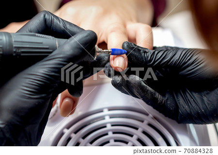 Manicurist applying electric nail file drill 70884328