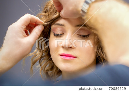 Hairdresser checks curly hairstyle of woman 70884329