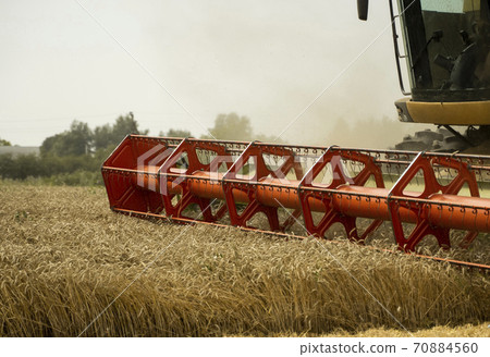 Combine harvester agriculture machine harvesting golden ripe wheat field. Agriculture. Combine harvester harvesting wheat with dust straw in the air. Heagy agricultural machinery. Combine harvester agriculture machine harvesting golden ripe wheat field. Agriculture. Combine harvester harvesting wheat with dust straw in the air. Heagy agricultural machinery. 70884560