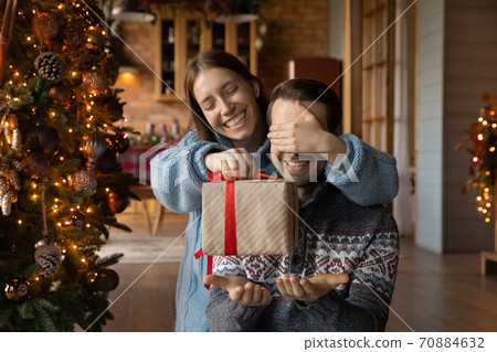 Happy woman make Christmas surprise for excited husband 70884632