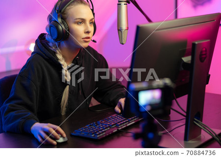 Professional e-sport gamer girl streaming and plays online video game on PC 70884736