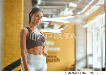 Young attractive fitness woman in sportswear with perfect body looking aside while standing at gym 70885116