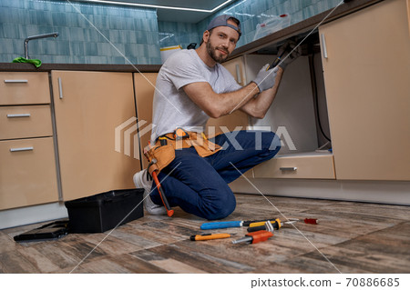 Young caucasian home master screwing part of kitchen furniture 70886685