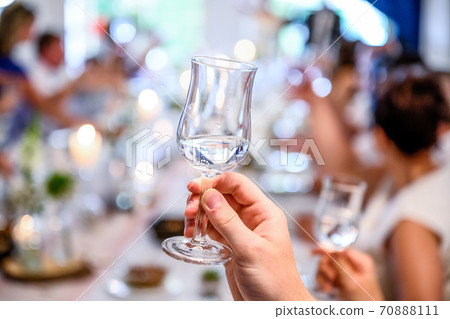 Wedding or party concept. Hand with a glass of vodka guest makes a toast, raising a glass 70888111