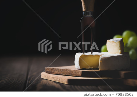Sliced Camembert with fork on cheese platter on dark background Sliced Camembert with fork on cheese platter on dark background 70888502