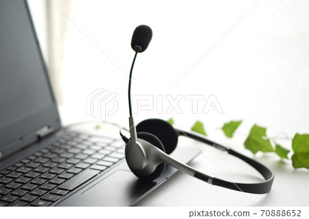 A computer and headset on a white background, and a green ivy. A computer and headset on a white background, and a green ivy. 70888652