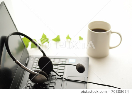 Computer and headset, coffee and green ivy on a white background. Computer and headset, coffee and green ivy on a white background. 70888654