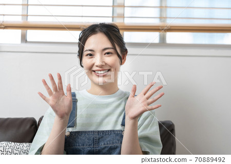Young woman waving her hands looking at camera Young woman waving her hands looking at camera 70889492