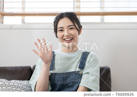 Young woman waving at camera Young woman waving at camera 70889926
