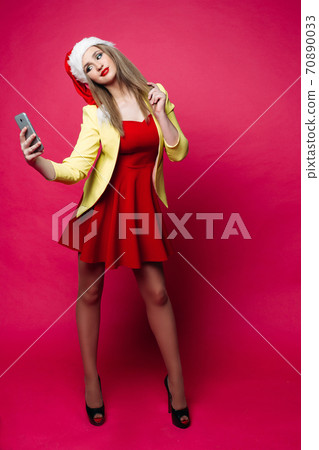 Surprised woman in santa hat making selfie over 70890033