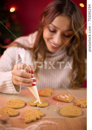 Christmas baking. cute smiling brunette young woman icing Christmas gingerbread 70890294